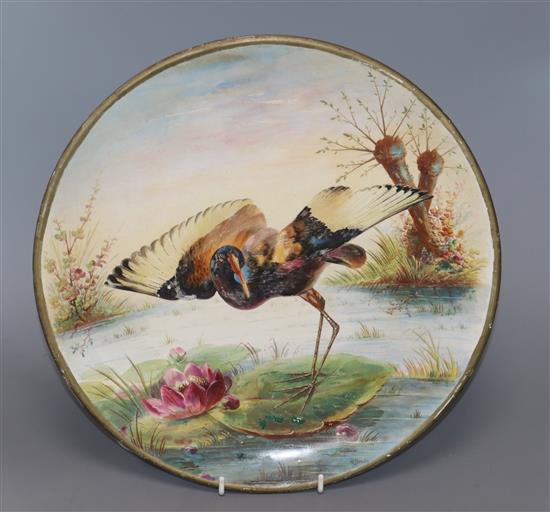 A ceramic charger painted with a Jacana standing on a lily pad by H. Deakin, Dia 32cm (worn)